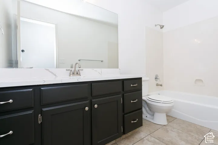 Dark wood vanity with brushed nickel hardware, white countertop, tile flooring, and a white bathtub with shower