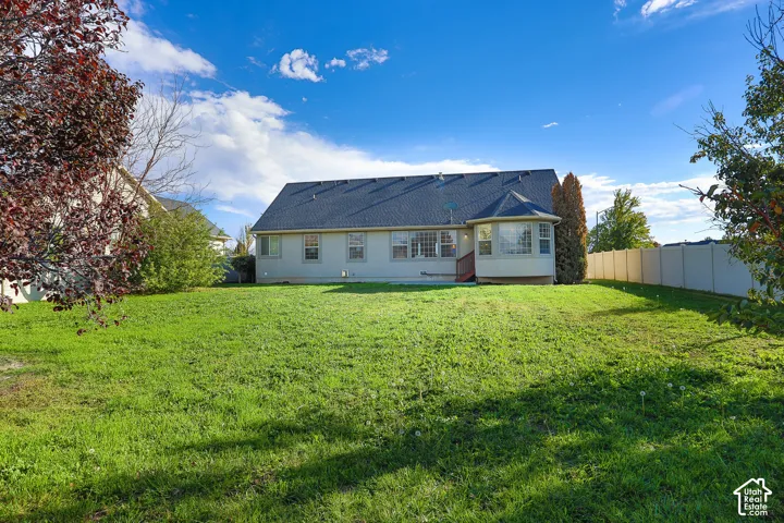 Expansive backyard with a manicured lawn, a rounded bay window, and a light-colored privacy fence