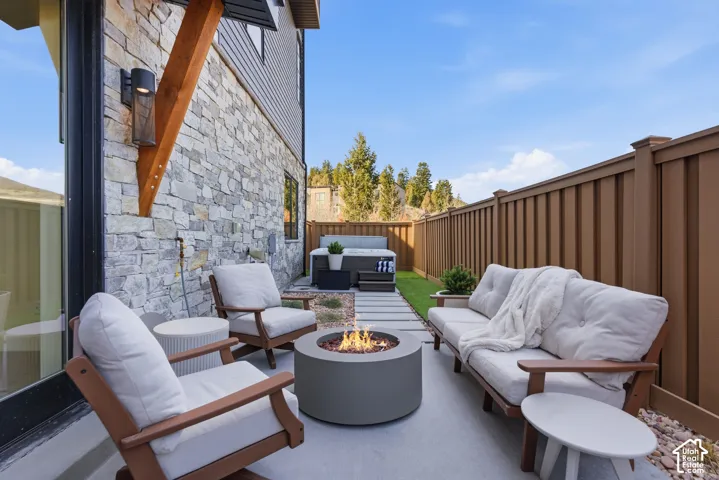 Expansive patio featuring a built-in fire pit, wood-beam pergola, and composite decking