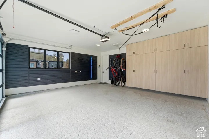 Epoxy-coated flooring, wood-finish cabinetry, built-in wall organization, and a glass-paneled garage door