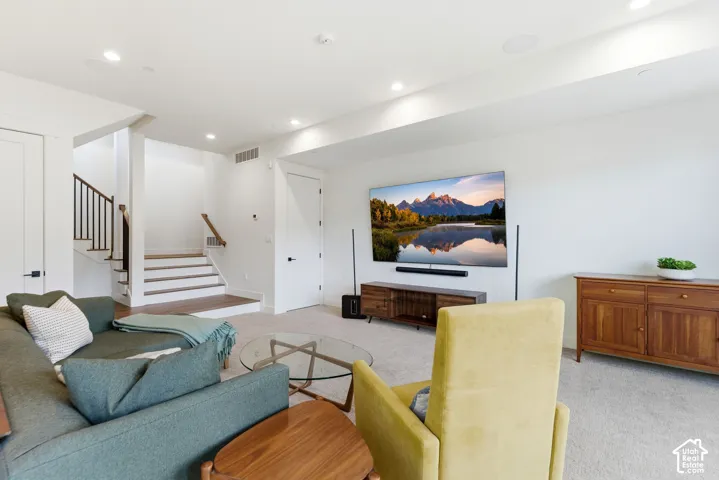 Recessed lighting, wood-finish stair treads, carpeted flooring, built-in ceiling speakers, and matte black door hardware