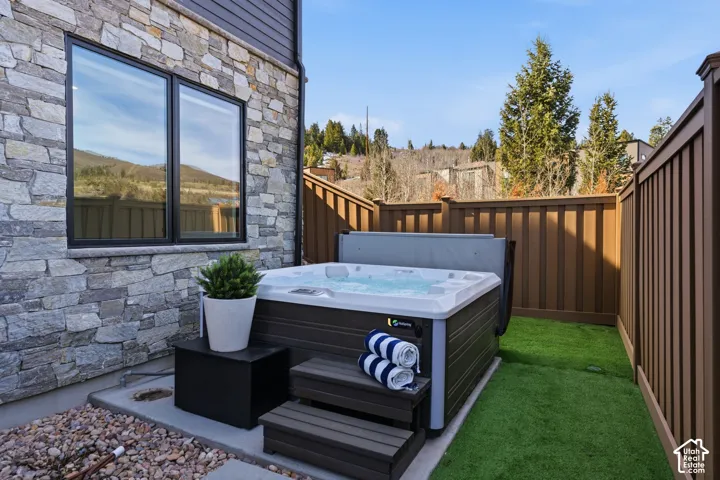 Outdoor spa tub with integrated steps, surrounded by artificial turf and privacy fencing