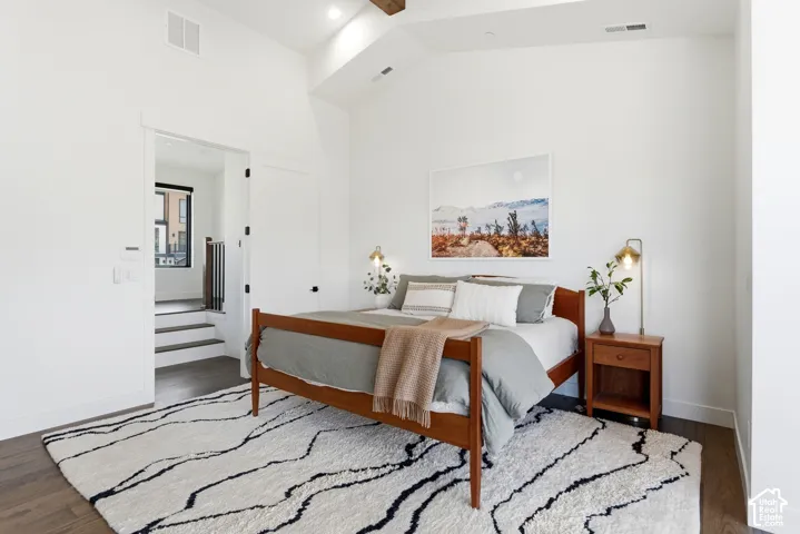 Vaulted ceiling with exposed wood beam, recessed lighting, and wood-finish flooring