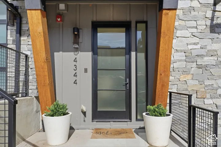 Entryway featuring a stone facade, wood support beam, and a paneled glass door with a sidelight