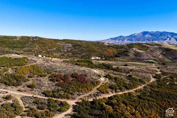 Mountainous terrain with natural vegetation, clear blue sky, and distant mountain range