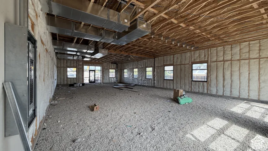 Unfinished interior space with exposed ceiling joists, multiple windows, and a large doorway