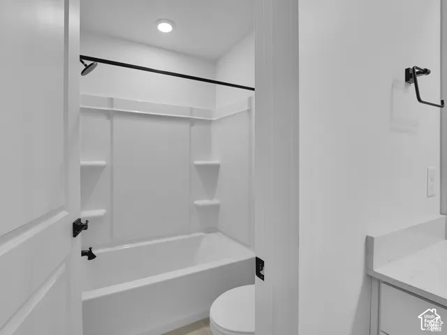 Bathtub with white surround and matte black fixtures, recessed lighting, and a white countertop vanity