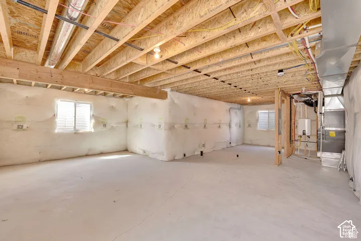 Unfinished lower level featuring an exposed ceiling, two windows with horizontal blinds, and a concrete floor