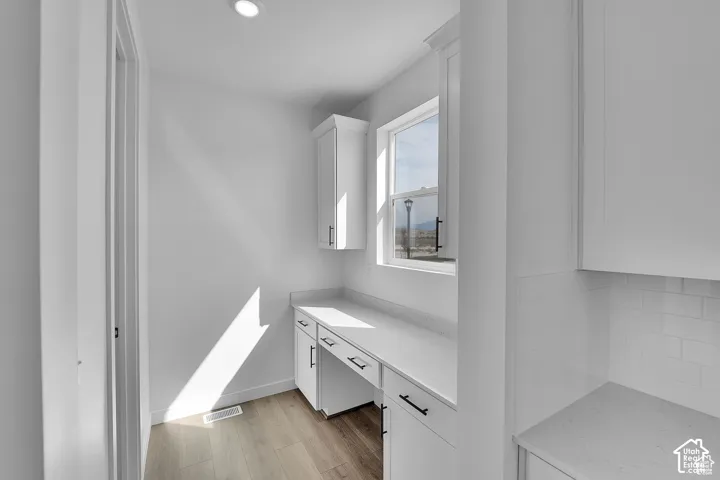 Built-in desk with white cabinetry and dark hardware, accompanied by a single window