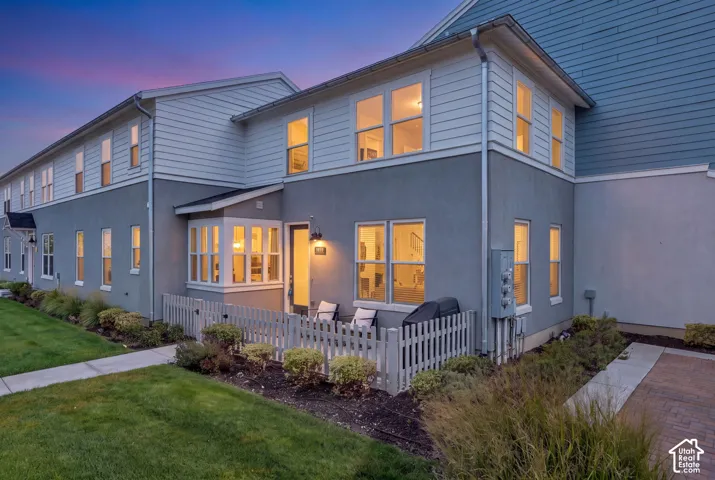 Multi-story exterior featuring a private patio, white picket fence, and a combination of stucco and horizontal siding