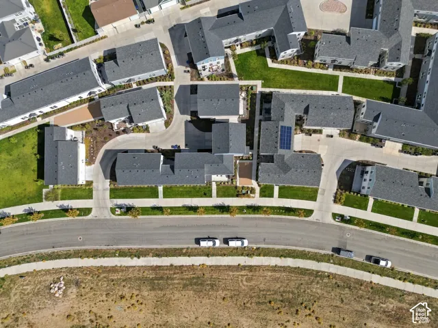 Residential community featuring multiple buildings with dark gray shingle roofs, manicured green spaces, paved pathways, and solar panels on select rooftops