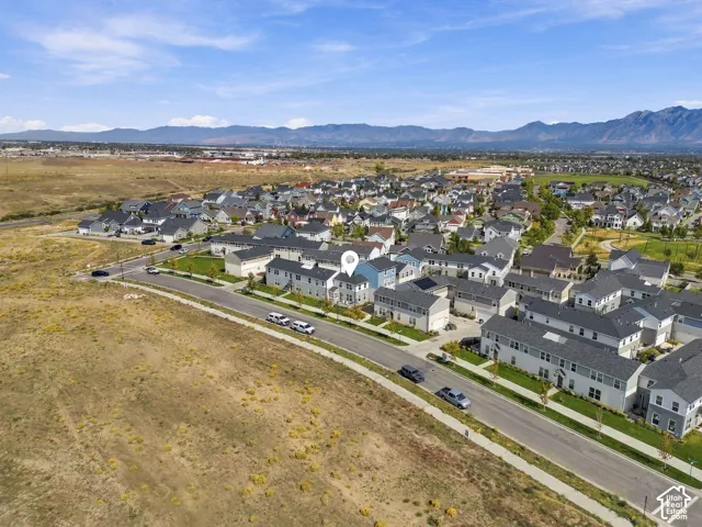 Residential development with multi-story homes, surrounded by natural terrain and distant mountains