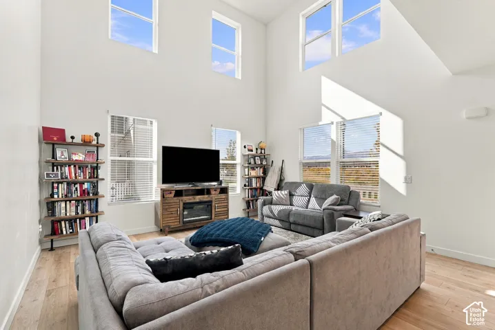 Vaulted ceiling in a spacious living area featuring wood-finish flooring, an integrated electric fireplace, and multiple windows
