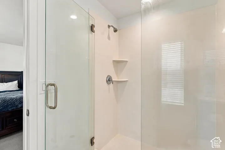 Glass-enclosed shower with a chrome showerhead and built-in corner shelving