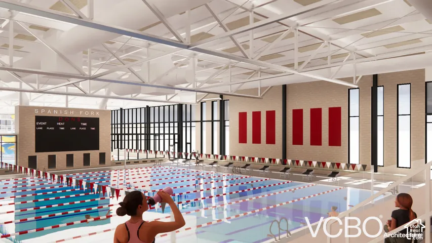 Indoor swimming pool with multiple lanes, a large integrated scoreboard, exposed ceiling trusses, and ample natural light from tall windows