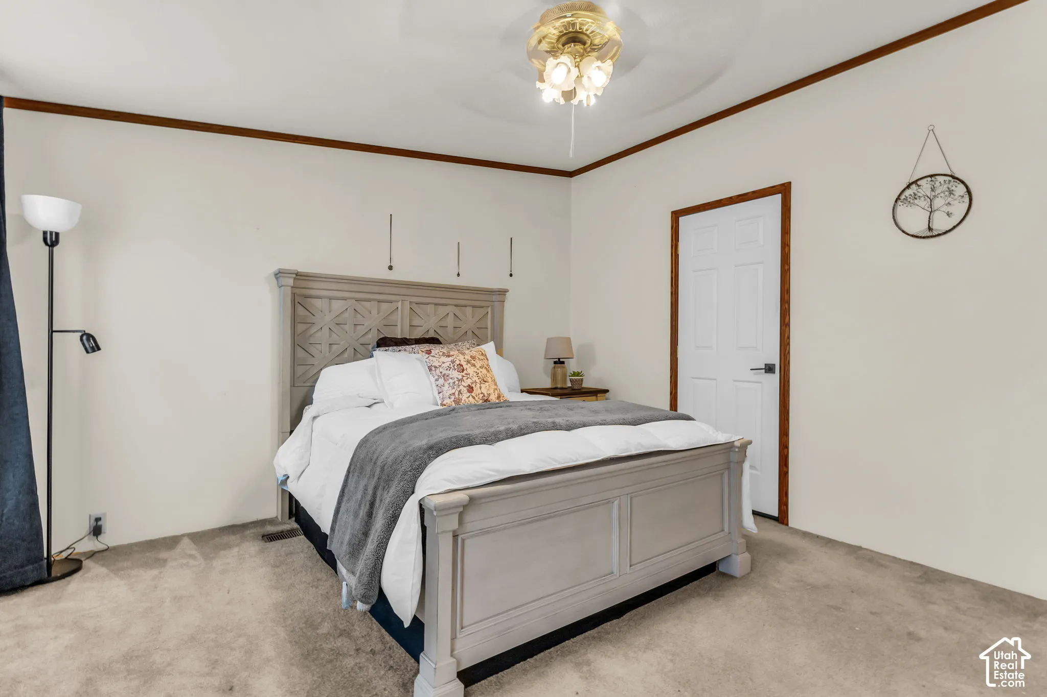 Plush carpet flooring, ceiling fan with integrated lighting, wood trim details, and a paneled interior door