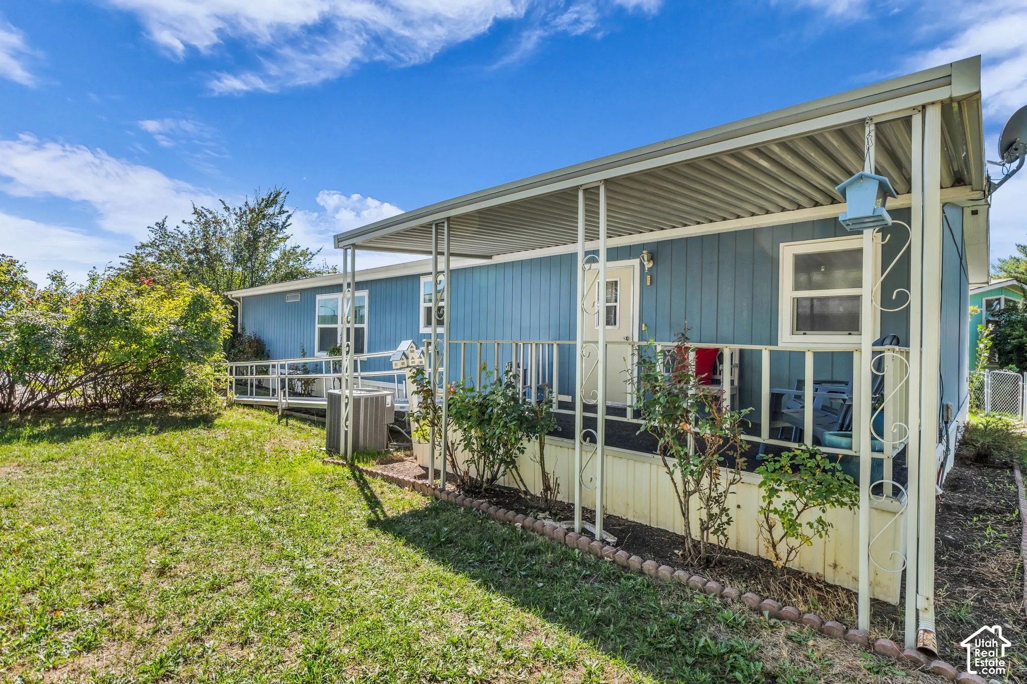 Covered porch with metal railing, blue exterior siding, and a white entry door