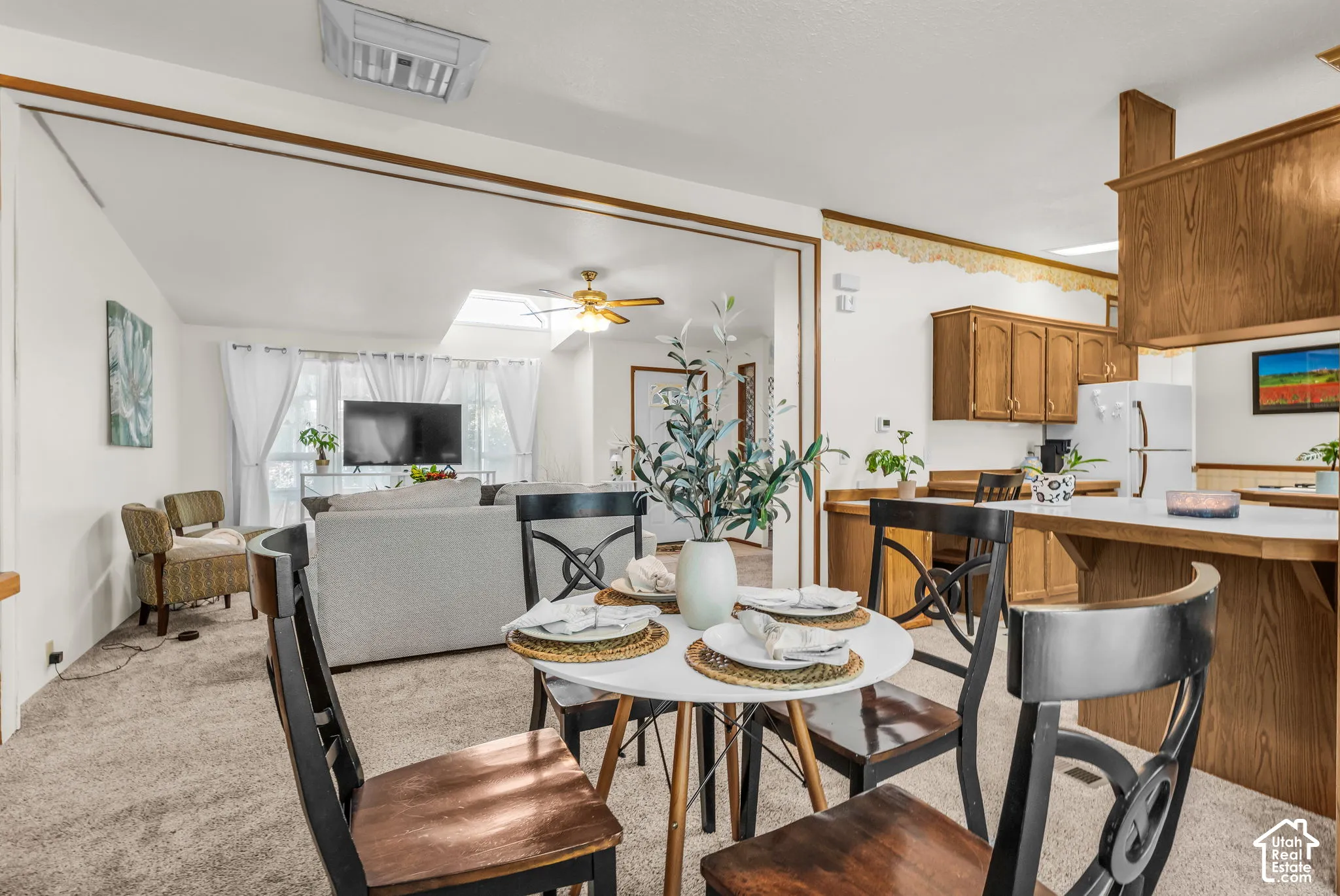 Open-concept living space featuring wood-finish cabinetry, white countertops, and a skylight