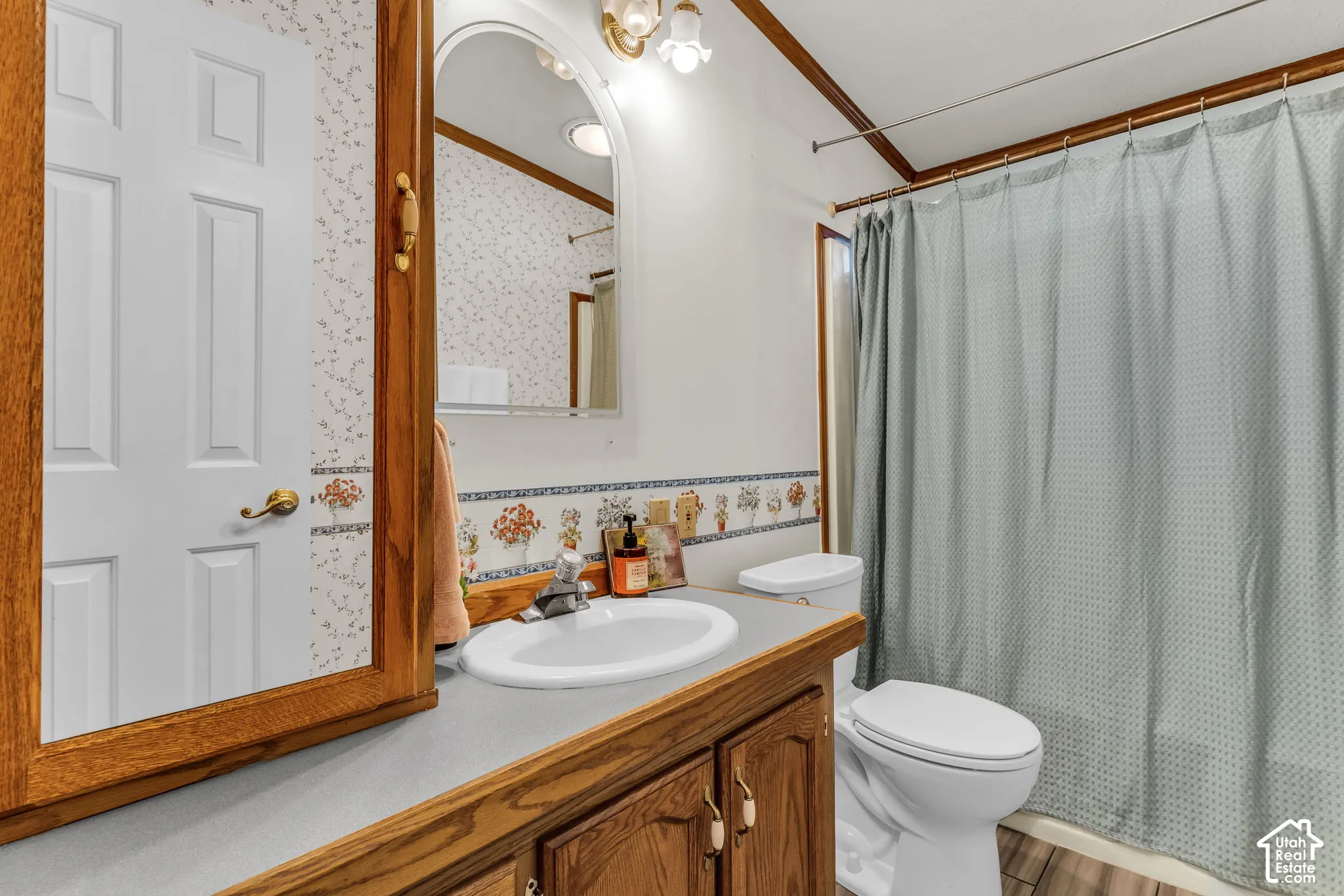 Bathroom with wood-finish vanity, integrated sink, and wall-mounted mirror