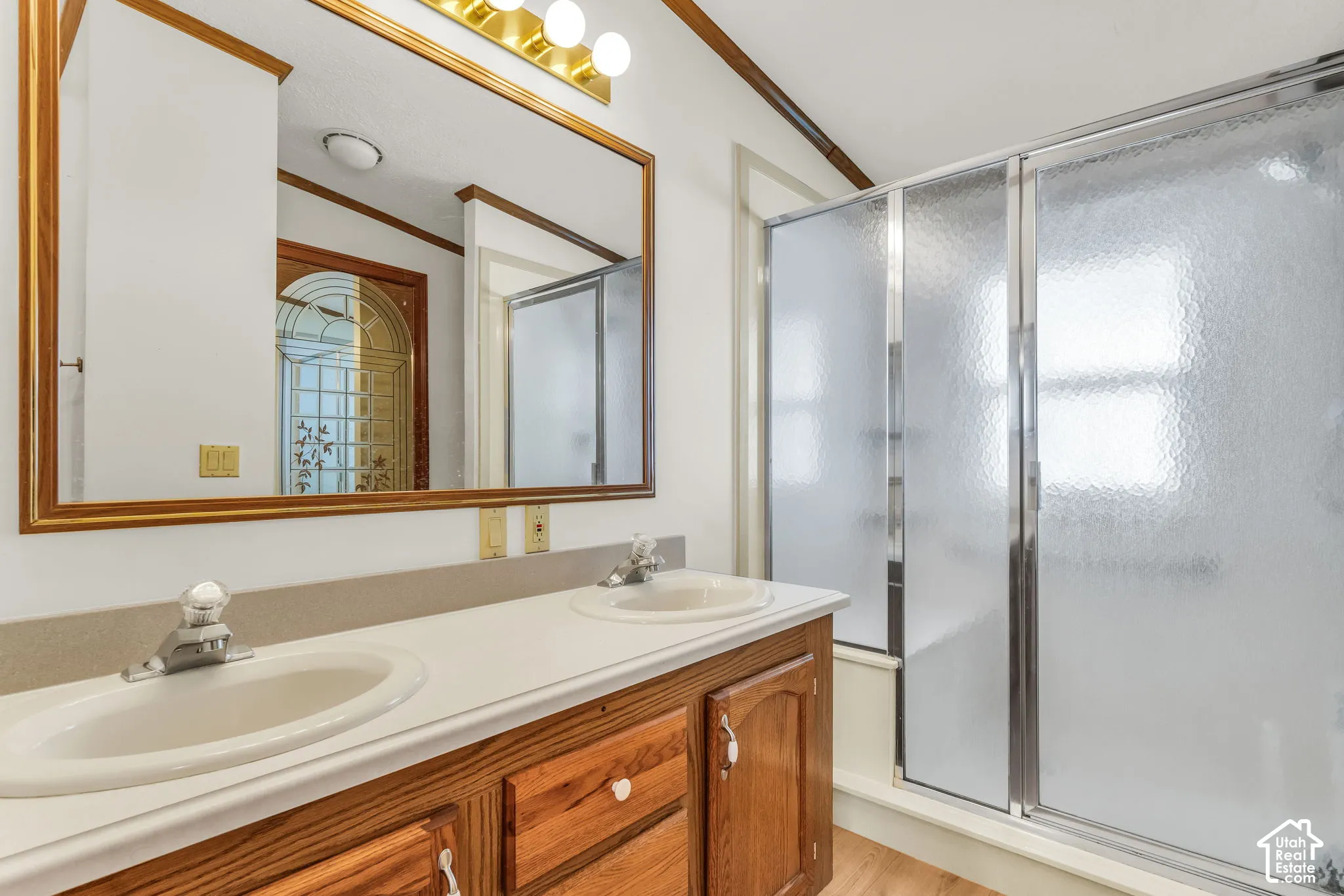 Dual vanity with integrated sinks, wood-finish cabinetry, and a framed mirror