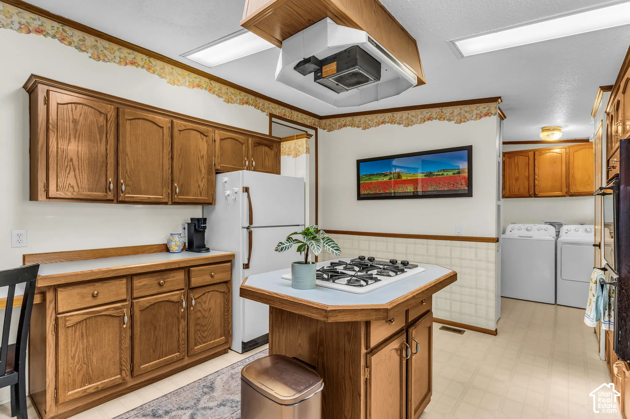 Kitchen featuring wood-finish cabinetry, a built-in island gas cooktop, and a utility area with appliance hookups