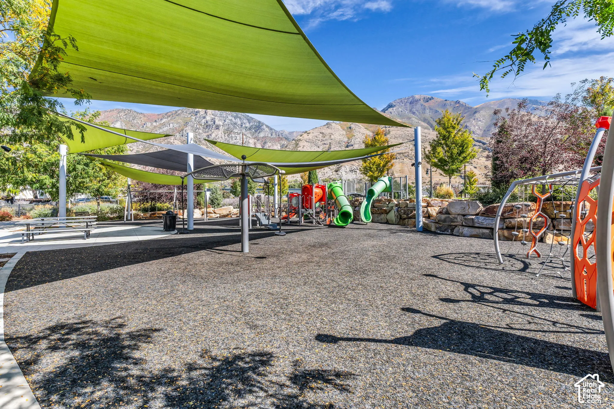 Community playground featuring shade structures, play equipment, and a soft-surface ground cover
