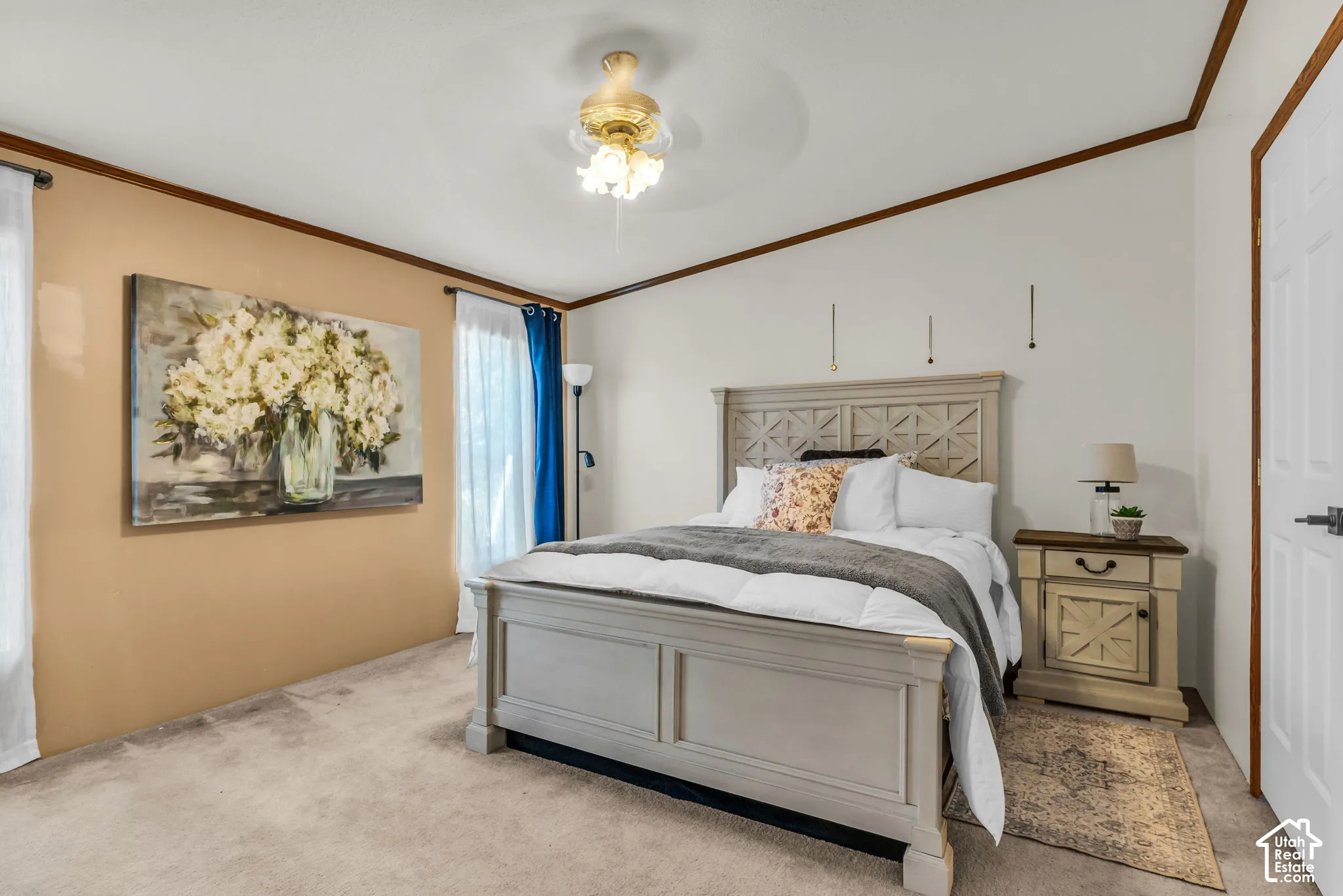 Neutral carpet flooring, vaulted ceiling, ceiling fan with integrated lighting, wood-trim molding, and a paneled door