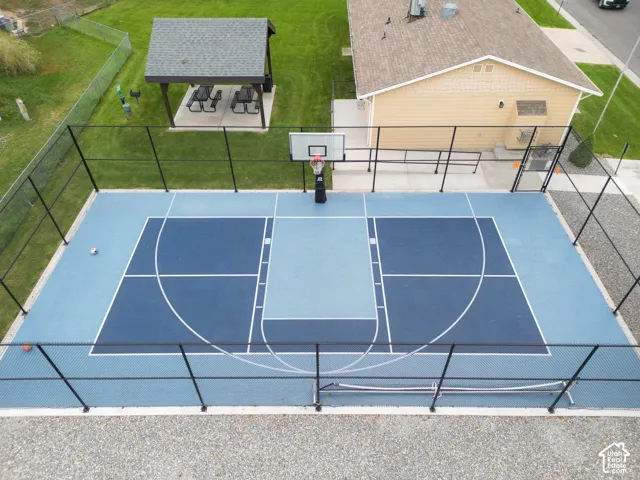 Outdoor sports court with perimeter fencing, a freestanding basketball hoop, and a nearby covered picnic area