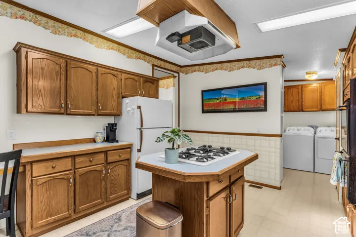 Kitchen featuring wood-finish cabinetry, a built-in island gas cooktop, and a utility area with appliance hookups