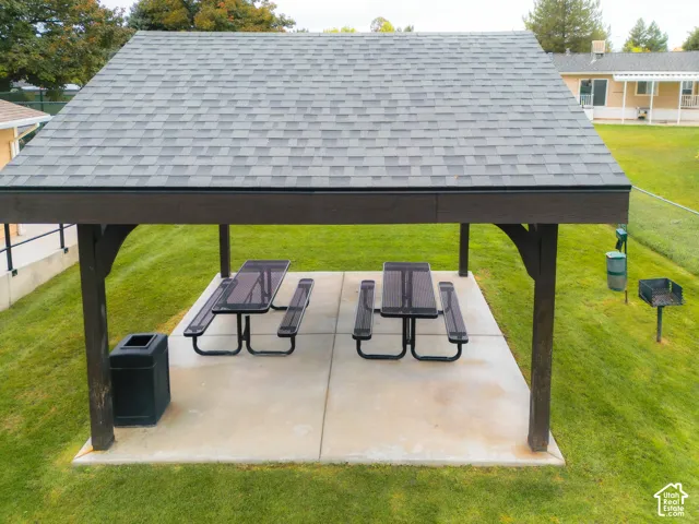 Shingled roof pavilion with exposed structural beams, featuring a concrete pad