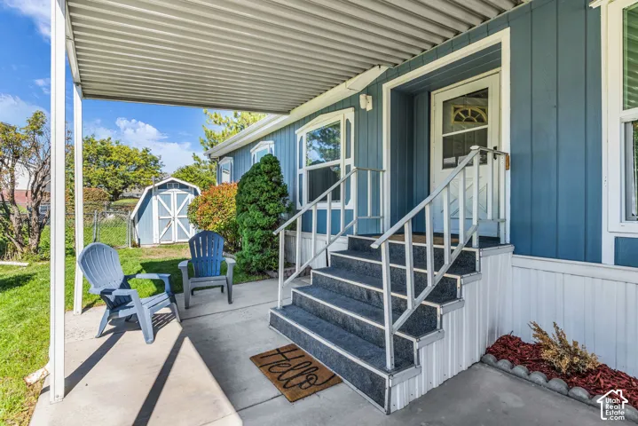 Covered concrete patio with blue siding, white trim, and a prominent front door