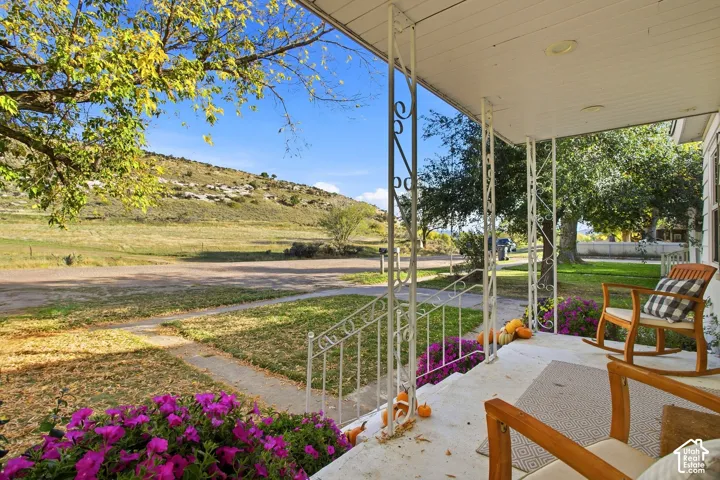 Covered front porch with decorative metal railings, concrete flooring, and recessed lighting