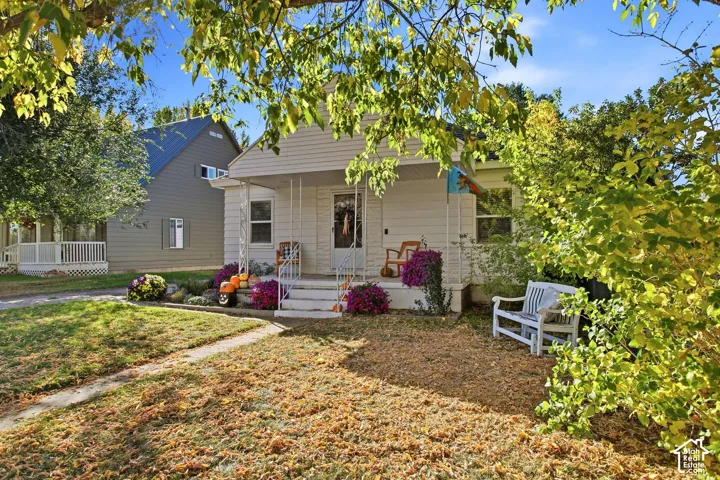 Front elevation featuring a covered porch, white siding, and mature landscaping