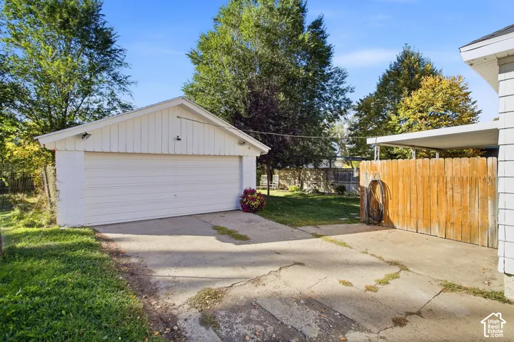 Detached garage with a single overhead door, concrete driveway, and wood privacy fencing