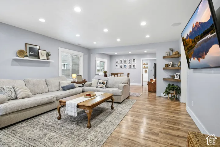 Recessed ceiling lighting, wood-finish flooring, white window trim, and built-in floating shelves