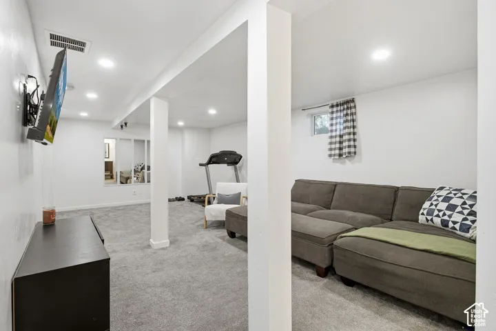 Recessed lighting, light-colored walls, and gray carpeting create a bright interior
