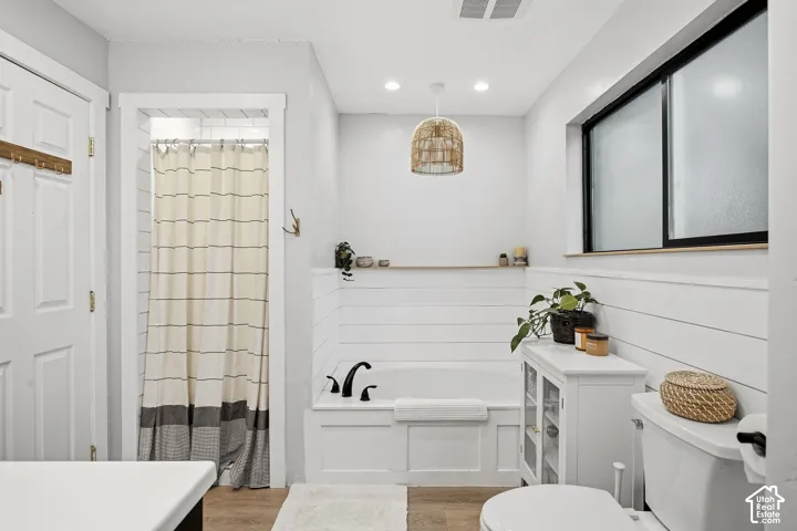 Built-in soaking tub with shiplap wainscoting, recessed lighting, and a decorative pendant light fixture