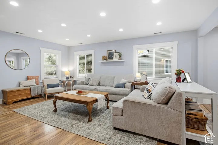 Recessed lighting, wood-finish flooring, white window trim, and a white floating shelf