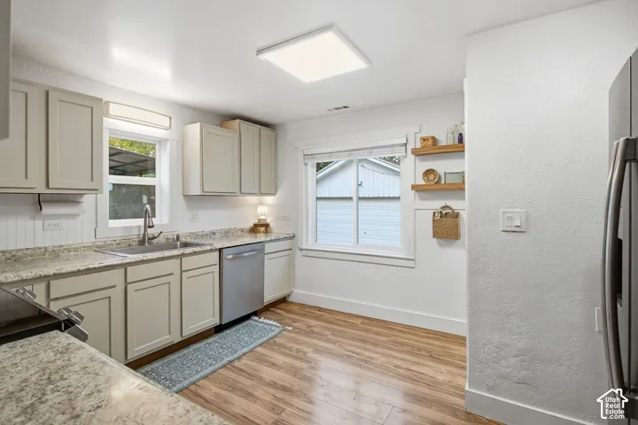 Kitchen featuring wood-finish flooring, light-toned cabinetry, stainless steel appliances, and built-in wood shelving