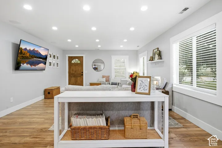 Recessed ceiling lighting, durable wood-finish flooring, white trim details, and a paneled entry door with an arched window