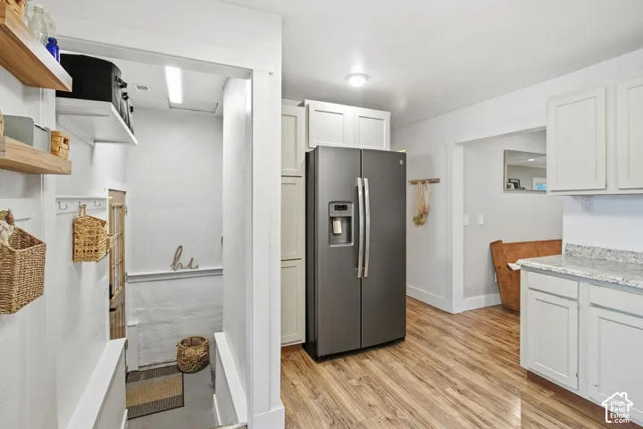 Kitchen featuring white cabinetry, light-toned granite-style countertops, wood-finish flooring, a stainless steel refrigerator, and recessed lighting
