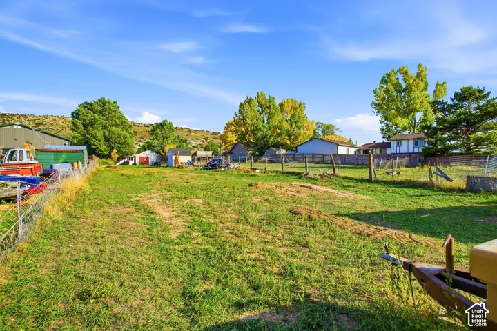Expansive grassy lot featuring wire fencing and distant natural landscaping