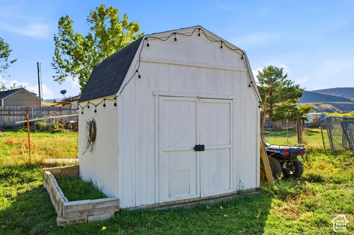 White-sided storage shed with a gambrel roof and double front doors