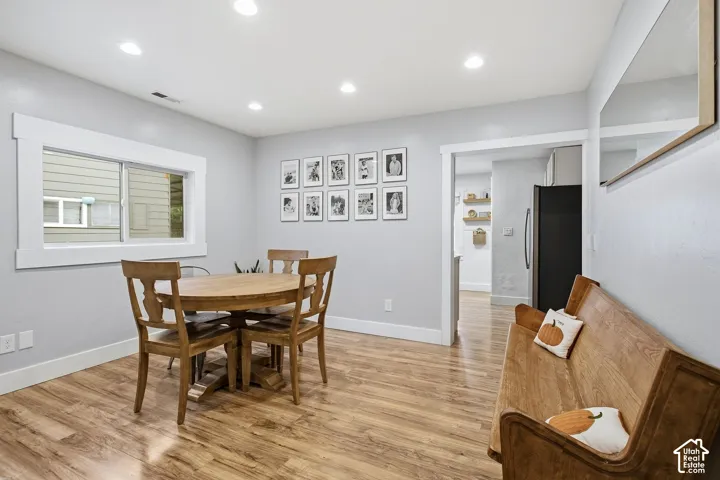 Recessed lighting illuminating wood-finish flooring, white trim details, and a functional window