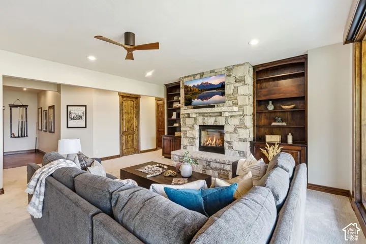 Stone-faced fireplace with a built-in firebox, flanked by custom wood built-in shelving, recessed lighting, and a ceiling fan