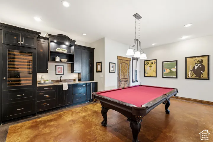 Wet bar with dark wood cabinetry, integrated wine refrigerator, and stone countertop