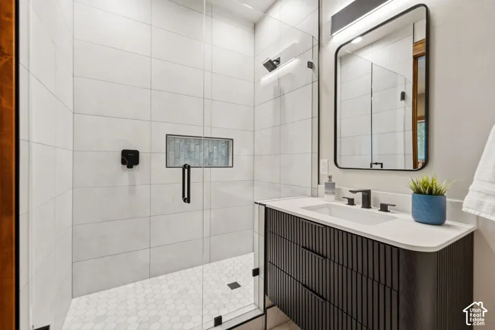 Glass-enclosed shower with white hexagon tile flooring and a built-in shelf