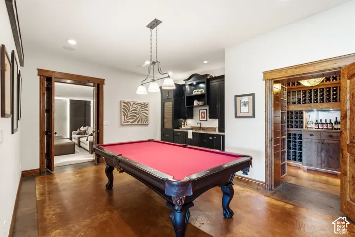 Wood-finish flooring, recessed lighting, and a built-in wet bar with dark cabinetry