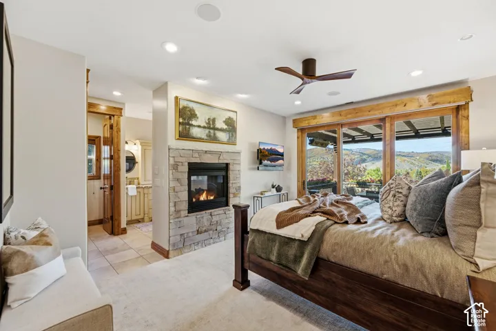 Built-in stone fireplace, ceiling fan, recessed lighting, expansive glass sliding doors, and wood-frame patio access
