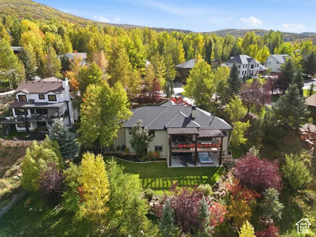 Expansive property featuring a multi-level deck, integrated hot tub, and lush hillside landscaping